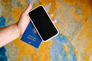 Mobile phone and a Ukrainian passport in the hands of a man close-up. Mobile application in your smartphone for unlimited travel. Tourism concept, vaccination passports for travelers via phone