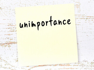 Yellow sheet of paper with word unimportance. Reminder concept - obrazy, fototapety, plakaty