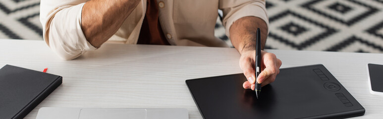 cropped view of designer drawing on graphic tablet on desk at home, banner