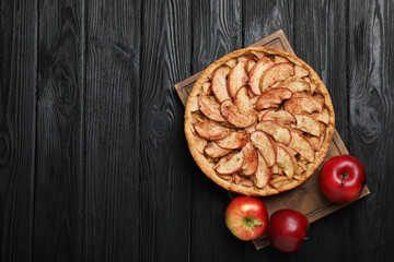 Delicious apple pie and fresh fruits on black wooden table, top view. Space for text