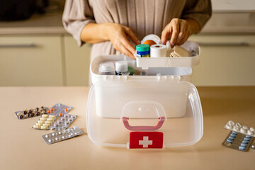 Closeup female hand placing medicament domestic first aid kit. Storage organization emergency supply - obrazy, fototapety, plakaty