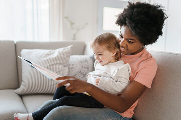 nursery babysitter with baby reading a book - obrazy, fototapety, plakaty