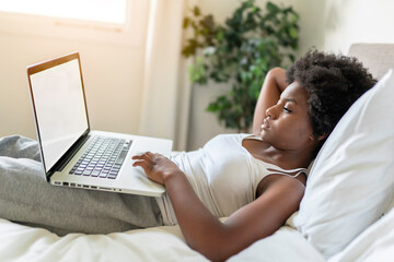 young black woman using a laptop in bright bedroom