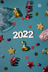 Fototapeta na wymiar Christmas, Happy New Year 2022 colorful flat lay with champagne, glass and stars, streamers. Creative layout for winter holidays