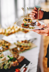 male hands take a snack and put it on plate. buffet in a restaurant
