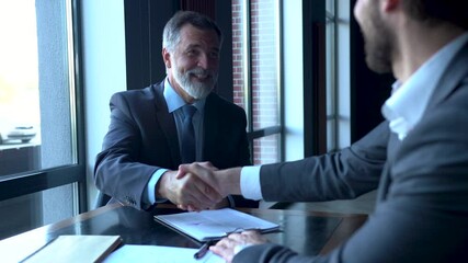 Business partners meeting in office building lobby and greeting with handshake