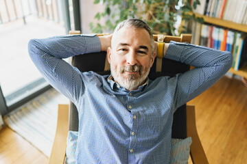 nice Joyful mature man at home appartement with grey beard relaxing on chair