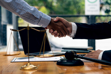 Fototapeta na wymiar On a table with scales and hammers placed in front of the businessman shakes hands, making a deal with a lawyer. male judge legal counsel Contract consulting services to plan a lawsuit in court