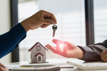 Real estate agents hand out keys to customers after signing the lease. Or buy a home with a home loan and home insurance deals at the table. in a 2-person office