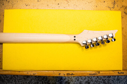 Wooden guitar neck against yellow sheet of paper