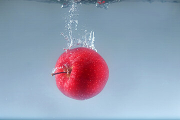 Apple falls into water on a light background