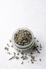 jar of unfermented pure and clean green tea from highlands of sri lanka, has a unique taste, on a textured white surface, taken from above