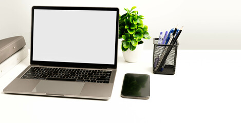 Copy space on right for design or text, Closeup, Gray, and blurred background, Blank white screen laptop on a white table in an office. Working concept using technology smartphones, notebook, internet