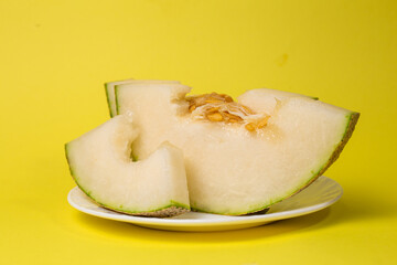 Slices Of Ripe Melon On a Plate on a yellow background