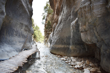 Wooden bridge along the rocky mountain and clear water stream in Samaria Gorge, Crete, Greece