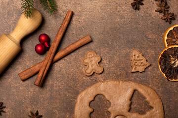 Gingerbread dough, a gingerbread man cookie, a Christmas tree cookie, cinnamon sticks, dried lemon slices, star anise fruits, a rolling pin, red Christmas tree ornaments. Holidays are coming.