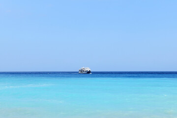 Fototapeta na wymiar Light blue and marine blue sea or ocean and a big small ship at the horizon 