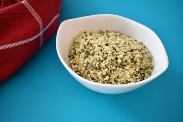 Hemp seeds in a white bowl on a blue table mat