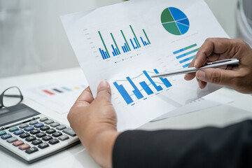 Asian accountant working and analyzing financial reports project accounting with chart graph and...