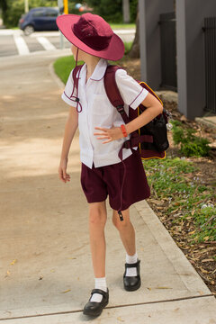 A girl wearing maroon school unfiform walking to school alone. School students return to classrooms after COVID-19 outbreak