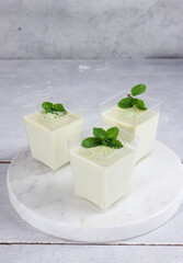 Green Tea Pana cotta in a glass decorated with mint leaf.