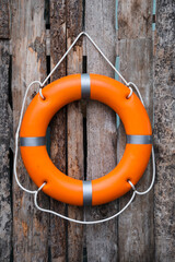Orange life buoy hanging on wooden wall