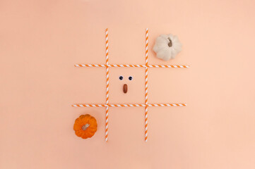 Tic-tac-toe game (OX game) with pumpkins on the orange background. Helloween composition. Creative composition.