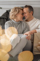 adult man and woman sit on the floor near the couch and hug