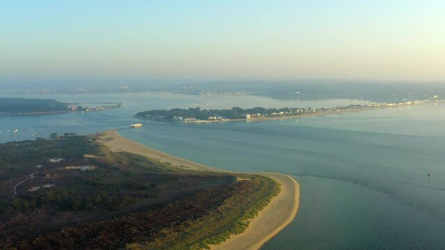 A sweeping aerial shot of Poole Harbour, Sandbanks, Brownsea Island and Studland beach at golden hour with calm peaceful sea