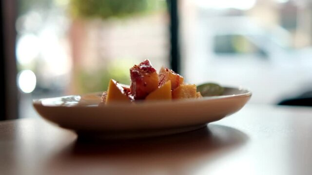 Plate of chopped mango with Mexican chamoy sauce and blurry background