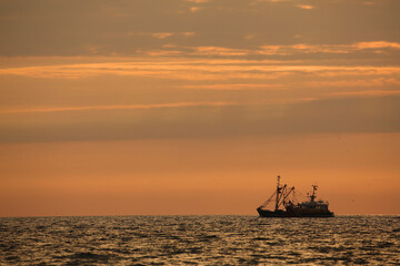 A fishing boat on the open sea at sunset