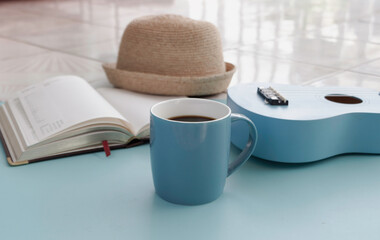 Blue ceramic cup with black coffee put beside Ukulele
