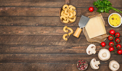 Ingredients for cooking pasta mushrooms cherry tomatoes parsley and parmesan cheese on wooden background with copy-space