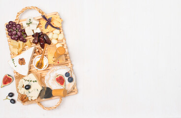 Cheese plate or cheese board with various type of cheese grapes dates uts fig and honey on white background with copy-space.