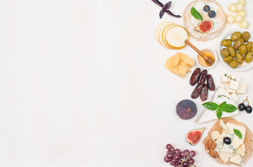 Fototapeta na wymiar Various type of cheese grapes dates nuts fig and honey on white background with copy-space.