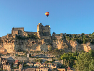 hot air balloon over dordogne castle from roadway
