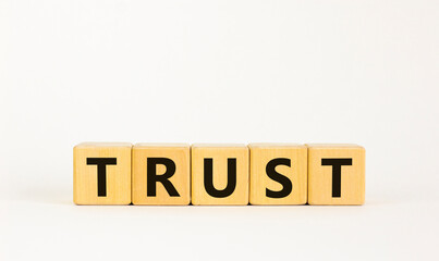 Trust symbol. The concept word 'trust' on wooden cubes. Beautiful white table, white background,...
