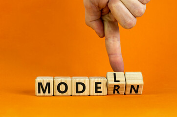 Modern model symbol. Businessman turns wooden cubes and changes the word 'model' to 'modern'. Beautiful orange table, orange background, copy space. Business and modern model concept.