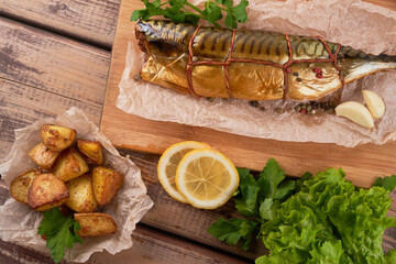Composition smoked mackerel fish with garnish potatoes lemon greens onions served on wooden board plate top view