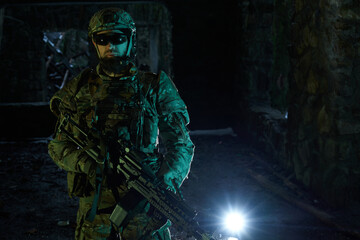 Portrait of airsoft player in professional equipment with machine gun in abandoned ruined building. Soldier with weapons at war