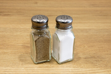 closeup of classic American diner style steel and glass salt and pepper shakers isolated on a wooden table