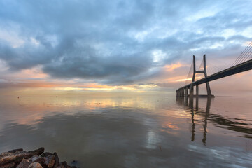 Background with colourful sunrise on the Lisbon bridge. The Vasco da Gama Bridge is a landmark, and one of the longest bridges in the world. Urban landscape. Portugal an amazing tourist destination.