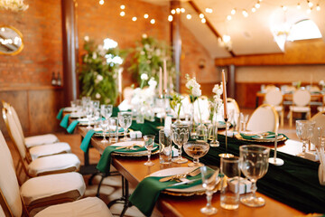 Banquet table in the restaurant, the preparation before the banquet. The work of professional florists in emerald color. Wedding, birthday, party, event concept.