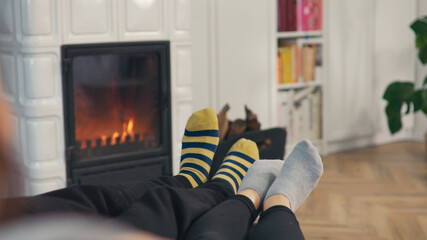 Close up of couple feet with hooped socks dancing in front of cosy fireplace - obrazy, fototapety, plakaty