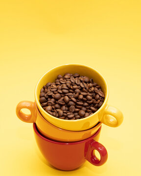 Three inspiring vibrant ceramic cups  of coffee beans with different colors, red, orange and yellow. Minimalist aesthetic style on bright yellow background. Top view vibrant colors.