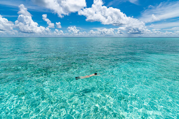 Woman snorkeling in clear tropical waters in front of exotic island
