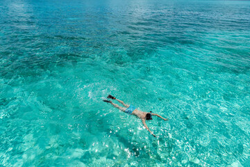 Man snorkeling in clear tropical waters in front of exotic island