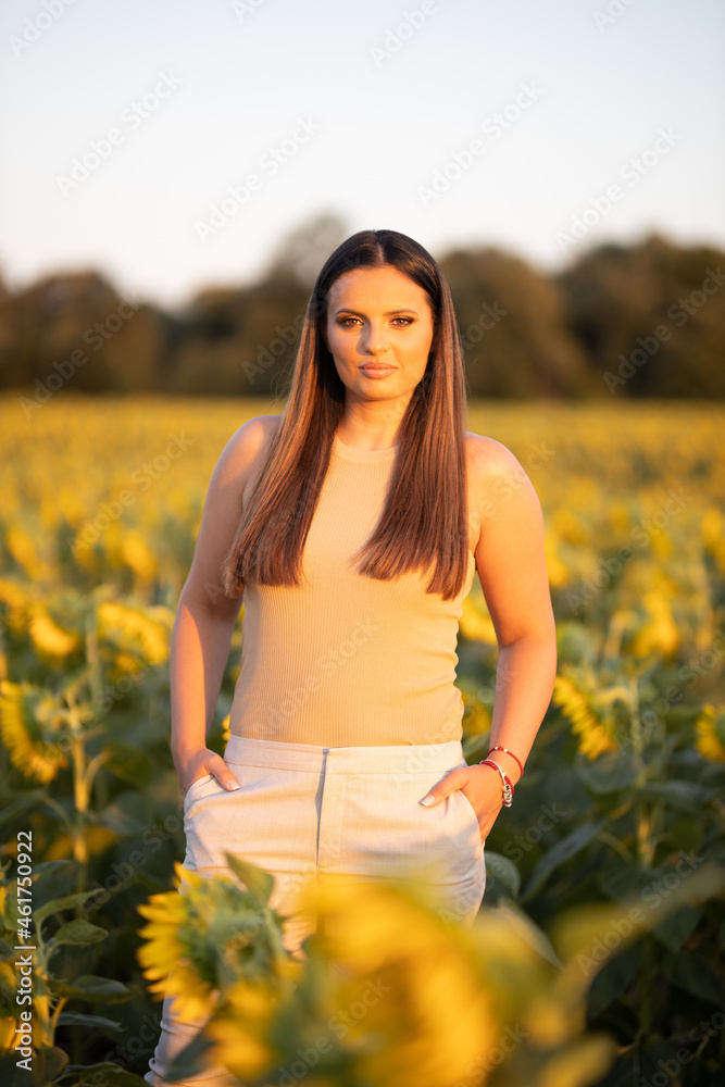 Poster Vertical shot of a white Caucasian woman posing for a picture in a sunflower field