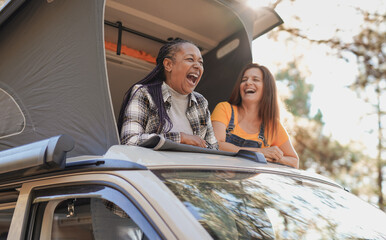 Mature multiracial friends enjoy vacation in the nautre with mini van - Senior women on a road trip with camper