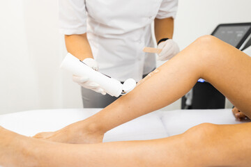 Obraz na płótnie Canvas Beautician applies a special gel for laser hair removal to a woman's leg